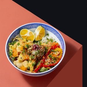 a blue and white bowl filled with food on top of a pink table